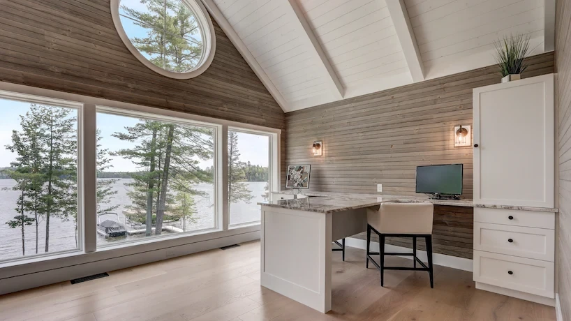 Newly renovated home office with wood flooring, granite desktop, and a massive window overlooking a bay